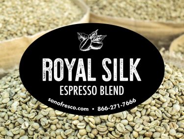 Royal Silk Espresso Blend label displayed in front of bags of green coffee beans.